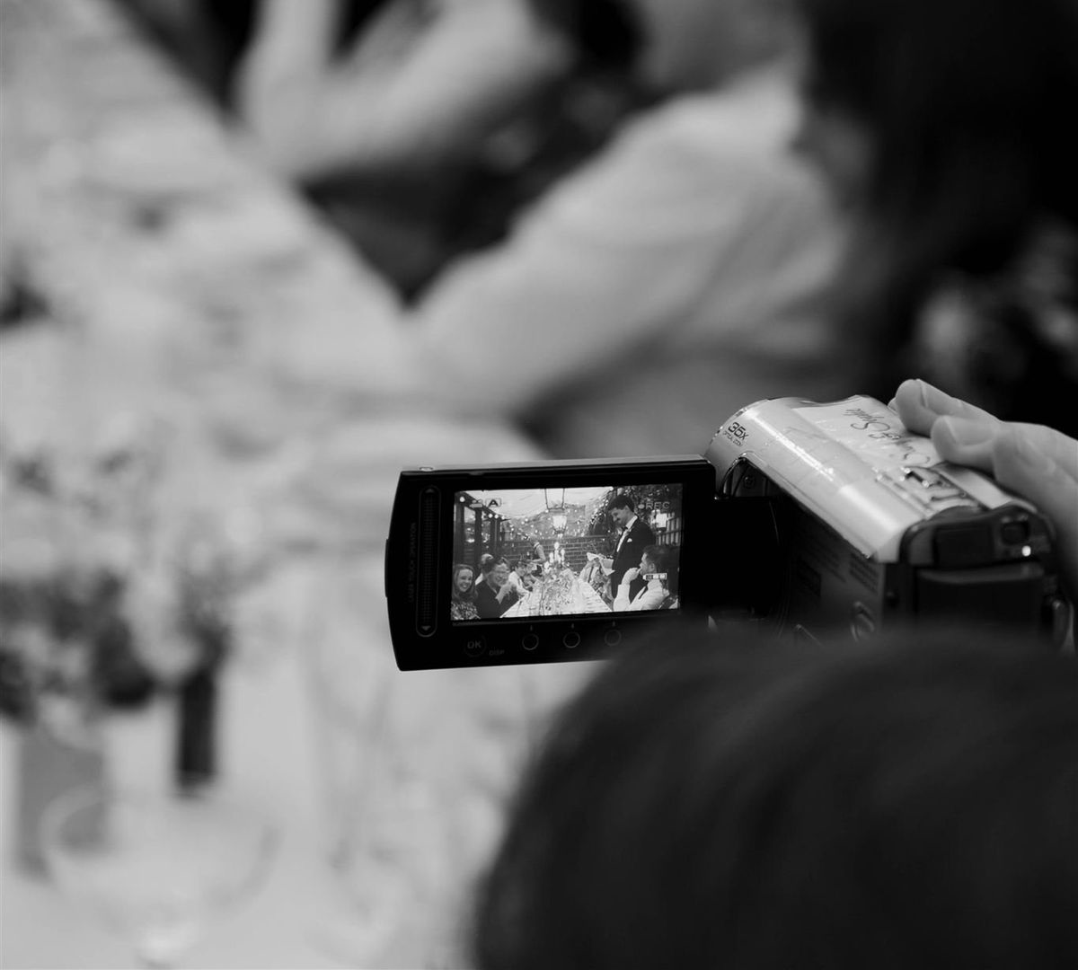 Wedding camcorder screen showing live footage being filmed at a UK wedding reception, raw unfiltered guest wedding video.